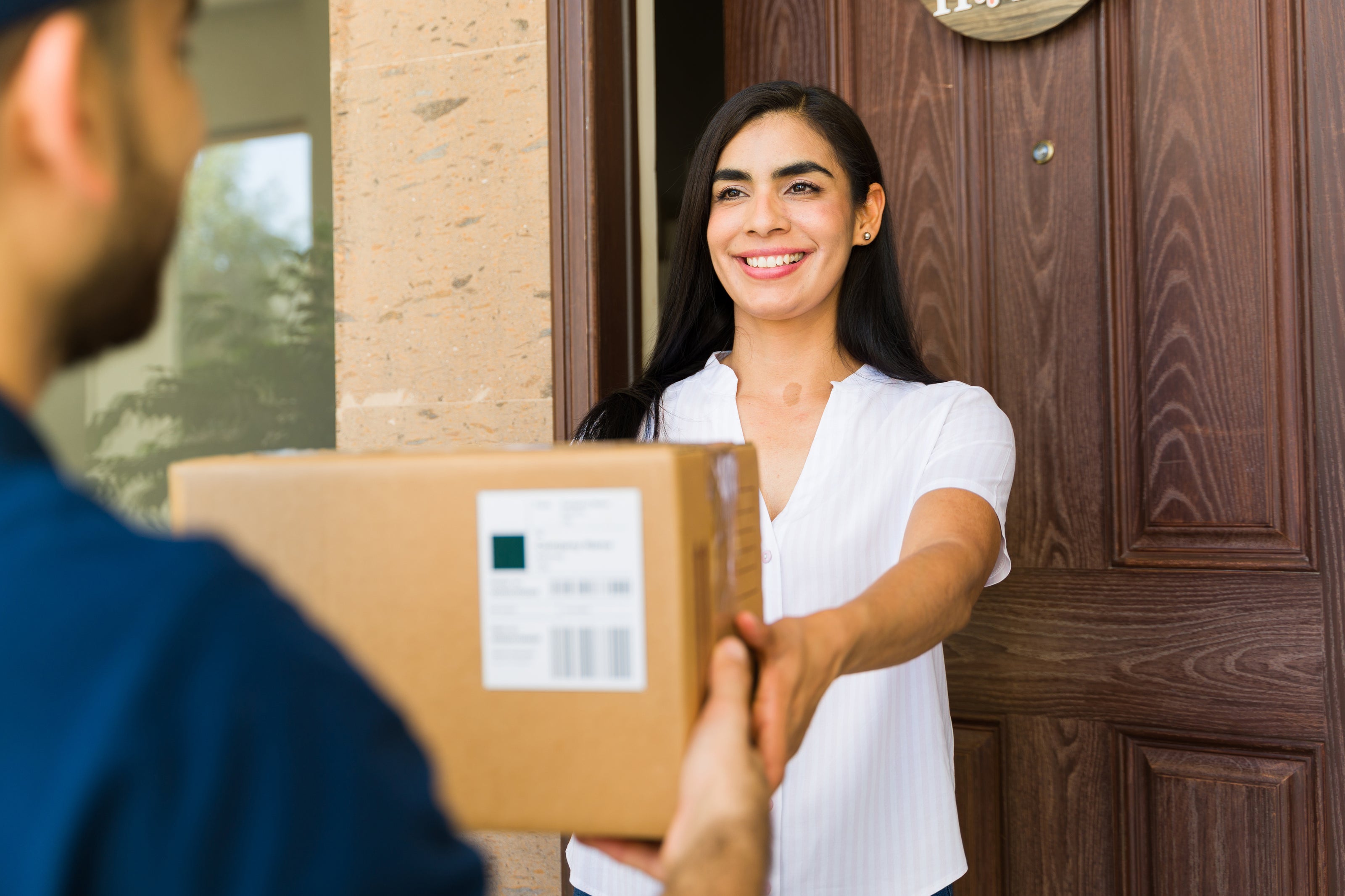 smiling woman receiving package from friendly delivery guy